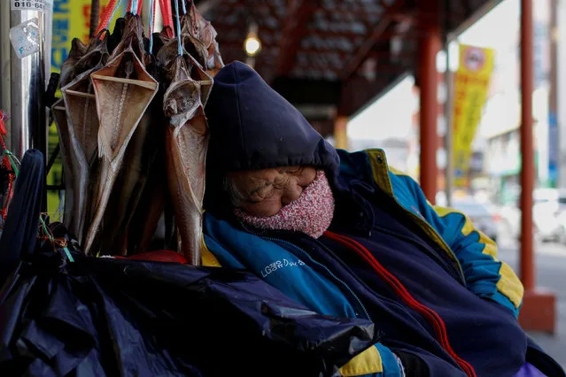 A vendor sleeps in a local market in Gangneung, South Korea, February 23, 2018. (Photo by Mike Segar/Reuters)