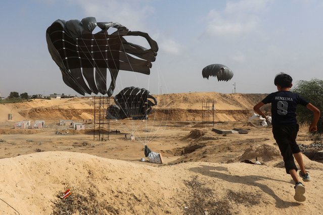 A Palestinian boy runs as aid packages are dropped from an airplane, amid a hunger crisis, in Deir Al-Balah, in the central Gaza Strip on August 12, 2025. (Photo by Ramadan Abed/Reuters)