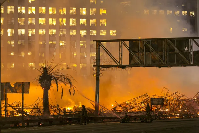 Los Angeles County firefighters battle a fire at an apartment building under construction next to the Harbor CA-110 Freeway in Los Angeles, early Monday, December 8, 2014. The building was not occupied, the Los Angeles Fire Department reported. (Photo by Damian Dovarganes/AP Photo)