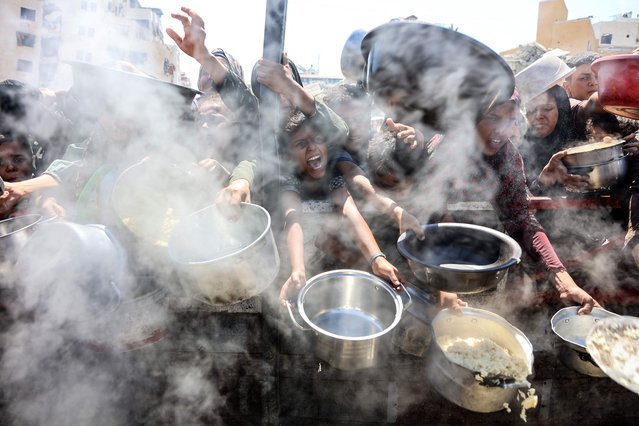 Palestinians extend empty pots in front of a charity kitchen to receive cooked rice, in Gaza City on August 23, 2025. The United Nations officially declared a famine in Gaza on August 22, blaming “systematic obstruction” of aid by Israel during more than 22 months of war, with Prime Minister Benjamin Netanyahu swiftly dismissing the findings. (Photo by Omar Al-Qattaa/AFP Photo)