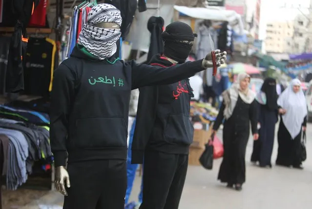 A mannequin holding a knife and wearing a jacket that reads: "Stab!" (L) is seen outside a clothes shop in Khan Younis, in the southern Gaza Strip November 3, 2015. In Gaza, a clothing store called "Hitler 2" has mannequins posed outside holding knives and dressed in T-shirts with "Stab!" written across the chests. (Photo by Ibraheem Abu Mustafa/Reuters)