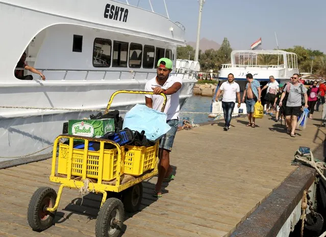 A man transports tourists belongings as they enter a yacht for an excursion at a small port of the Red Sea resort of Sharm el-Sheikh, November 7, 2015. (Photo by Asmaa Waguih/Reuters)