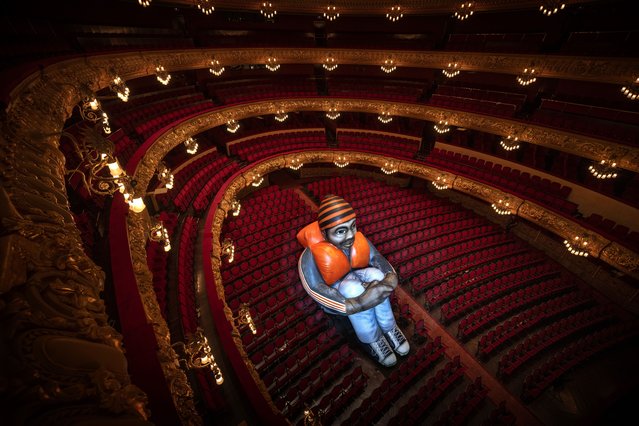 Sitting alone in a sea of empty red velvet chairs, a 6-meter-tall giant “Inflatable Refugee” is photographed at Barcelona's Gran Teatre de Liceu opera house, Spain, Wednesday, June 12, 2024. Created by Belgian visual artists Schellekens & Peleman in 2015 following the refugee crisis in Europe by, they hope it to spark debate around the plight of refugees. The artistic intervention coincided with an alarming record: 120 million people around the world have been forcibly displaced from their homes due to conflict and other protracted crises, the U.N. Refugee announced on Thursday. (Phoot by Emilio Morenatti/AP Photo)