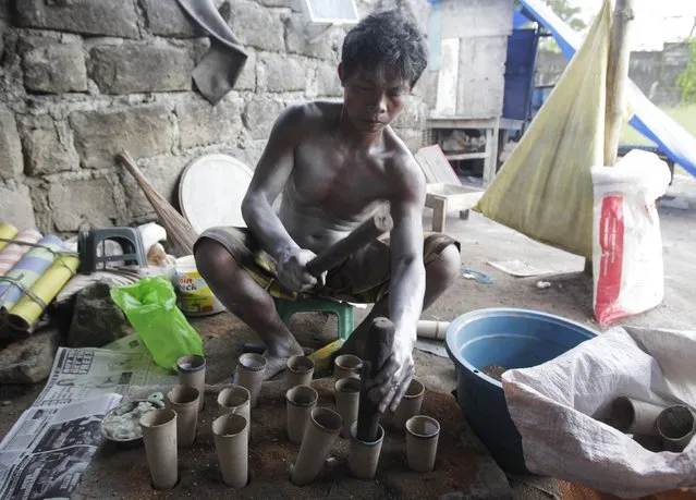 The body of a worker is covered in gunpowder as he makes firecrackers at a makeshift factory in Bocaue town, Bulacan province, north of Manila December 27, 2014. (Photo by Romeo Ranoco/Reuters)