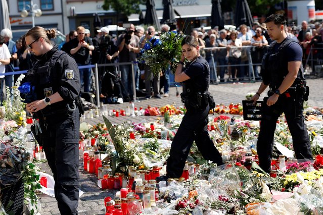 Police officers pay their respects at the site where a man attacked people with a knife at a far right-wing information stand and killed a policeman in the central market of the city of Mannheim, Germany on June 7, 2024. (Photo by Heiko Becker/Reuters)