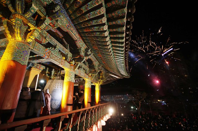 Buddhist monks and believers (L) hit a traditional bell as fireworks go off during a ceremony to celebrate the new year at Bongeun Buddhist temple in Seoul January 1, 2015. (Photo by Kim Hong-Ji/Reuters)