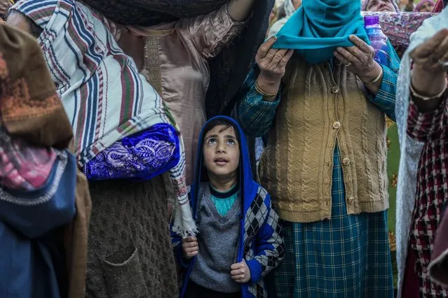 A Kashmiri Muslim boy stands with elders as the head priest displays a holy relic believed to be a hair from the beard of the Prophet Muhammad during special prayers to observe the martyr day of Hazrat Ali, the fourth caliph of Islam, at Hazratbal shrine in Srinagar, Indian controlled Kashmir, Wednesday, April 12, 2023. (Photo by Mukhtar Khan/AP Photo)