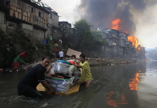 Residents salvage their belongings after a raging fire engulfed around 2,000 houses in Quezon city, metro Manila January 1, 2015. At least eight people, including a seven year-old child, died and thousands were displaced after a fire broke out in different locations in metro Manila as the New Year kicked off, local media reported. (Photo by Romeo Ranoco/Reuters)