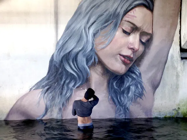 Artist Sean Yoro, standing in the shallows of the intra-coastal waterway, applies the finishing touches to his portrait of Clara under the Royal Park Bridge, the middle bridge between West Palm Beach and Palm Beach, Fla., on November 23, 2015. Yoro was one of 20 artists from all over the world who took part in the West Palm Beach Canvas Outdoor Museum Show. (Photo by The Palm Beach Post via ZUMA Wire)