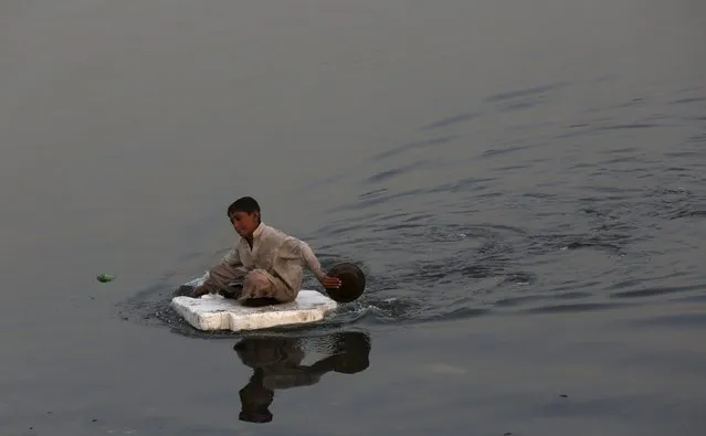 A boy sits on a piece of styrofoam sheet while searching for recyclables at China Creek in Karachi, Pakistan November 10, 2015. (Photo by Akhtar Soomro/Reuters)