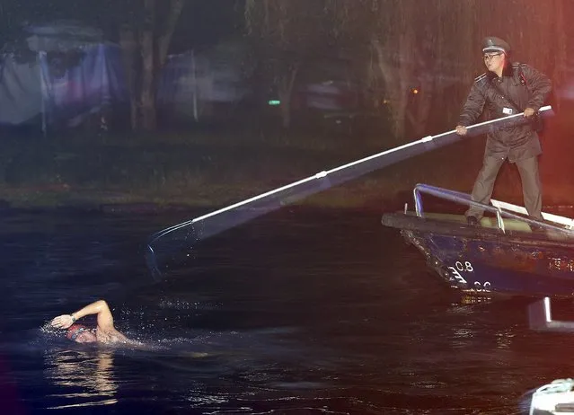 A security personnel (R) tries to stop a man from swimming away after being caught swimming in the West Lake, which is a violation of the resort's regulations, in Hangzhou, Zhejiang province, China, December 1, 2015. (Photo by Reuters/Stringer)