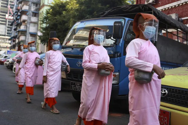 Buddhist nuns wearing face masks and shields to help curb the spread of the coronavirus walk to collect cash and rice from devotees Wednesday, February 3, 2021, in Yangon, Myanmar. (Photo by Thein Zaw/AP Photo)