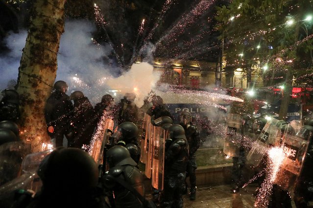 A firework explodes near police officers during a rally of opposition parties' supporters, who protest against the new government's decision to suspend the European Union accession talks, in Tbilisi, Georgia on November 30, 2024. (Photo by Irakli Gedenidze/Reuters)