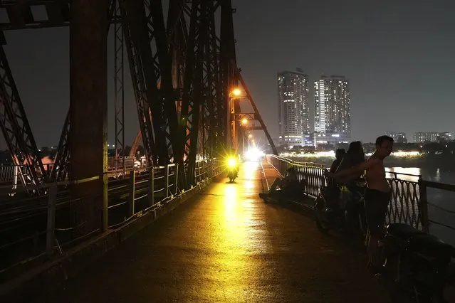 People rest on a bridge for cool breeze in Hanoi, Vietnam, on June 8, 2023. Vietnam has released a long-anticipated energy plan meant to take the country through the next decade and help meet soaring demand while reducing carbon emissions. (Photo by Hau Dinh/AP Photo)