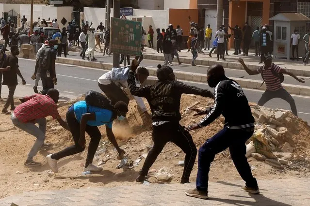 Supporters of opposition leader Ousmane Sonko hurl stones during clashes with security forces after Sonko's parliamentary immunity was lifted in Dakar, Senegal on March 3, 2021. Senegal's main opposition leader, Ousmane Sonko, was arrested on Wednesday after hundreds of his supporters clashed with police in the capital while protesting against a rape accusation he denies. (Photo by Zohra Bensemra/Reuters)