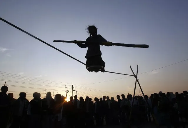 Tightrope walker Siba, 9, is silhouetted against the setting sun as she holds a balancing pole while performing on a rope, on the banks of river Ganga in the northern Indian city of Allahabad January 30, 2015. (Photo by Jitendra Prakash/Reuters)