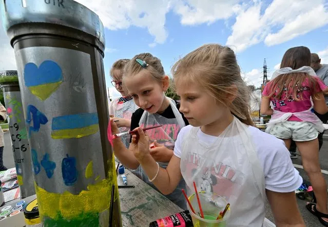 Ukrainian children paint shell casings for the local “Museum of Memory” during an art action in Bucha, north of Kyiv on June 30, 2023. (Photo by Sergei Supinsky/AFP Photo)
