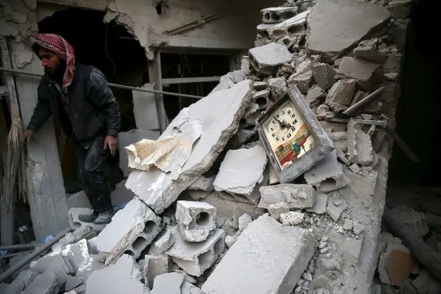 A man walks near a damaged clock in a site hit by what activists said were airstrikes carried out by the Russian air force in the town of Douma, eastern Ghouta in Damascus, Syria January 10, 2016. (Photo by Bassam Khabieh/Reuters)