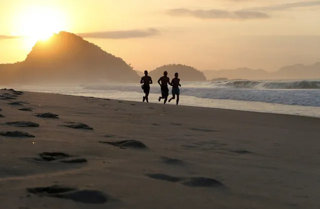 Men run along famous Copacabana Beach at sunrise, in Rio de Janeiro, Brazil, 30 July 2016. (Photo by Barbara Walton/EPA)