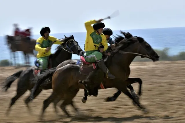 Riders compete during the match between Russia and Kazakhstan at World Kok-Boru Cup, also called ulak tartysh, a traditional game in which players on horseback manoeuvre with a goat's carcass and score by putting it into the opponents' goal at the Cholpon-Ata hippodrome, 250 km (155 miles) southeast of Bishkek, Kyrgyzstan, on Sunday, August 13, 2023. (Photo by Vladimir Voronin/AP Photo)