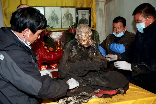 Workers remove charcoal and sandalwood debris from the mummified body of a monk during the unveiling ceremony at Puzhao temple, in Quanzhou, Fujian Province, China, January 10, 2016.  According to local media, the monk named Fuhou died three years ago at the age of 94 and his remains was placed in a vat and turned into a mummy as a sign of respect. (Photo by Reuters/Stringer)