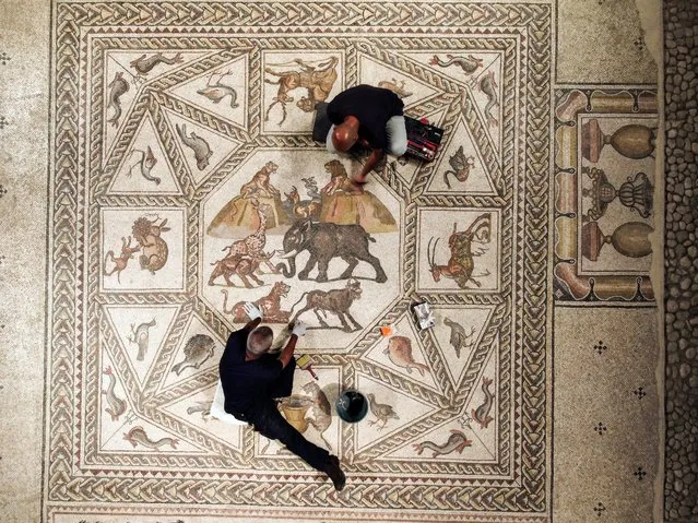 Workers clean a restored Roman-era mosaic after it was put on display at its original site in Lod, now an Israeli city where an archaeological centre has been inaugurated in Lod, Israel on June 27, 2022. (Photo by Amir Cohen/Reuters)