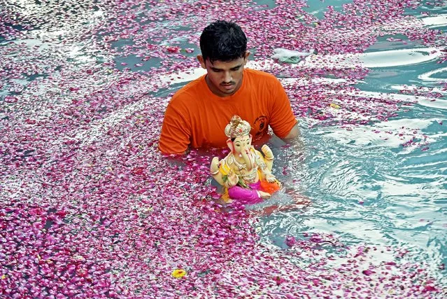 A devotee immerses an idol of elephant-headed Hindu god Ganesha in an artificial pond during Ganesh Chaturthi festival in Mumbai, India on September 20, 2023. (Photo by Aditya/NurPhoto/Rex Features/Shutterstock)
