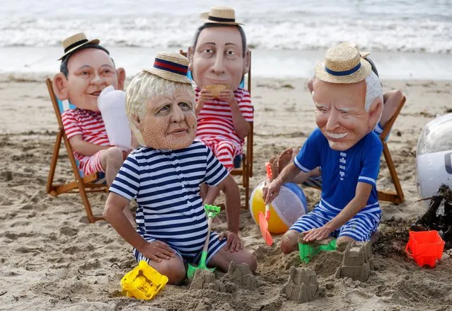 Oxfam activists wearing papier mache heads depicting Japan's Prime Minister Yoshihide Suga, Britain's Prime Minister Boris Johnson, Italy's Prime Minister Mario Draghi and U.S. President Joe Biden perform during a protest at Swanpool Beach near Falmouth, during the G7 summit, in Cornwall, Britain, June 12, 2021. (Photo by Phil Noble/Reuters)