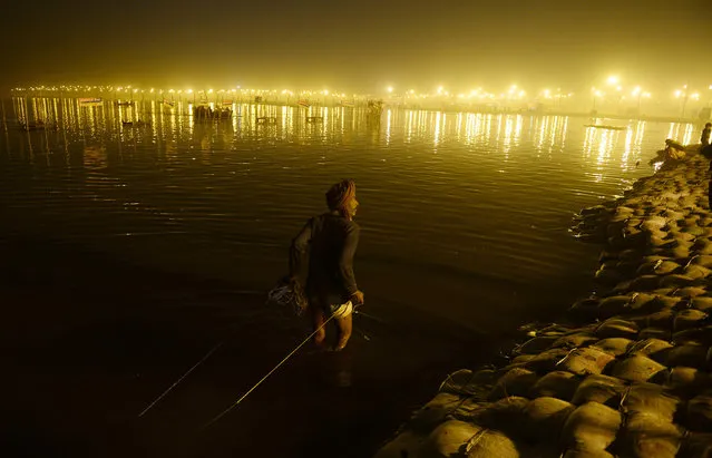 An Indian scavenger searches for coins offered by Hindu devotees at Sangam during the annual Magh Mela festival in Allahabad on February 5, 2016. (Photo by Sanjay Kanojia/AFP Photo)