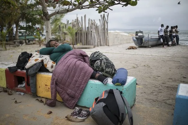 A migrant woman sleeps on a cement bench near the beach in Necocli, Colombia, Thursday, July 29, 2021. Migrants have been gathering in Necocli as they move north towards Panama on their way to the U.S. border. (Photo by Ivan Valencia/AP Photo)