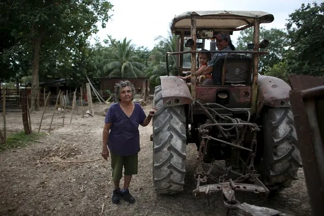 Sara Carcache (R), 40, sits with her daughter Saidy as her mother Candida Estrada, 76, looks to the camera beside a 1970 Ukrainian made tractor in Caimito, Cuba, February 15, 2016. (Photo by Alexandre Meneghini/Reuters)