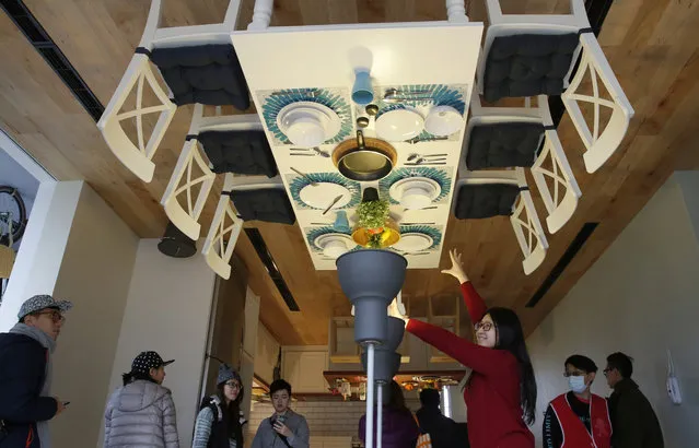 A visitor poses inside an upside-down house created by a group of Taiwanese architects at the Huashan Creative Park in Taipei, Taiwan, Tuesday, February 23, 2016. (Photo by Wally Santana/AP Photo)