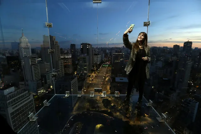 Influencer takes a selfie inside Sampa Sky, a reinforced glass box that protrudes beyond the building and allows to see not only the horizon, but also the ground below your feet, in downtown Sao Paulo, Brazil, August 3, 2021. (Photo by Amanda Perobelli/Reuters)