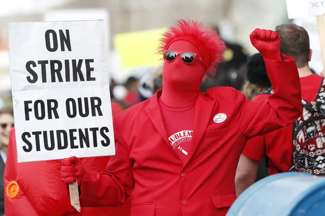 An instructor cheers while wielding a placard during a march to Denver Public Schools headquarters to deliver Valentine Day cards Wednesday, February 13, 2019, in Denver. Teachers walked off their jobs Monday, the first strike by teachers in Denver in 25 years. (Photo by David Zalubowski/AP Photo)