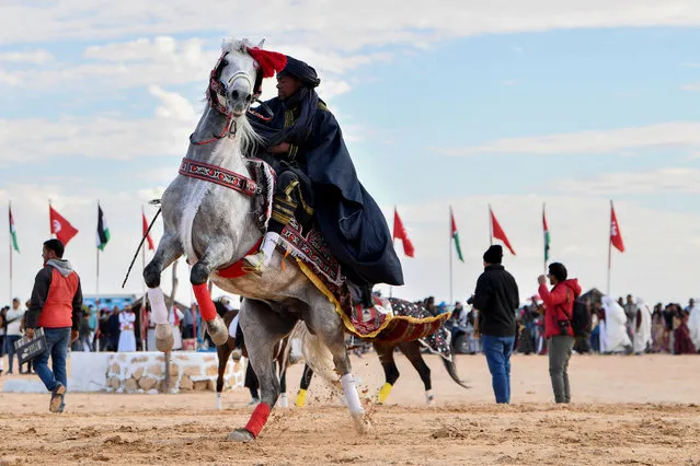 A performer wearing traditional outfit rides a horse at the start of the International Sahara Festival on December 27, 2023 in Douz, in southern Tunisia. (Photo by Fethi Belaid/AFP Photo)