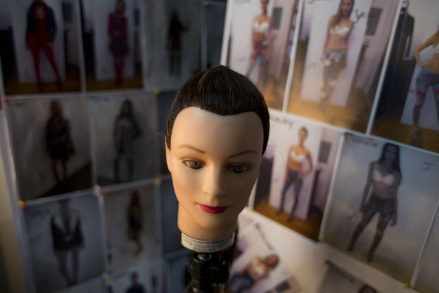 A mannequin head sits in front of photos showing which outfit each model will wear, backstage at Mercedes-Benz Fashion Week in Mexico City, Tuesday, April 14, 2015. (Photo by Rebecca Blackwell/AP Photo)