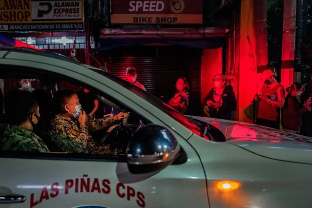 A police officer reminds people queuing for a COVID-19 vaccine to observe social distancing, outside a vaccination site on August 08, 2021 in Las Pinas, Metro Manila, Philippines. As a strict lockdown is reimposed in parts of the Philippines to curb the spread of the more contagious Delta variant of the coronavirus, Filipinos are defying curfew measures and flocking by the thousands to vaccination sites as early as midnight in hopes of getting vaccinated against COVID-19. The desperation comes after recent reports circulated that the government will not extend financial aid to unvaccinated individuals. While the presidential spokesperson denied this, President Rodrigo Duterte himself during one of his televised speeches that he will order police to jail unvaccinated individuals. (Photo by Ezra Acayan/Getty Images)