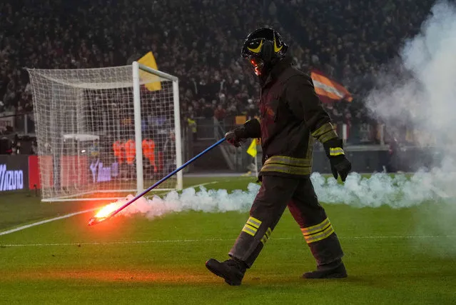 A firefighter removes a flare that landed on the pitch before the quarterfinal Italian Cup soccer match between Lazio and Roma at Rome's Olympic Stadium, Wednesday, January 10, 2024. (Photo by Gregorio Borgia/AP Photo)