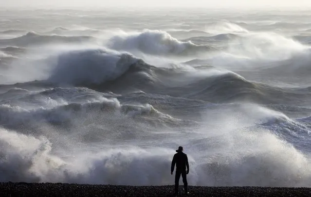 A person looks out towards the waves crashing on the shore in Newhaven on January 2, 2024, as Storm Henk was set to bring strong winds and heavy rain across much of southern England. (Photo by Adrian Dennis/AFP Photo)