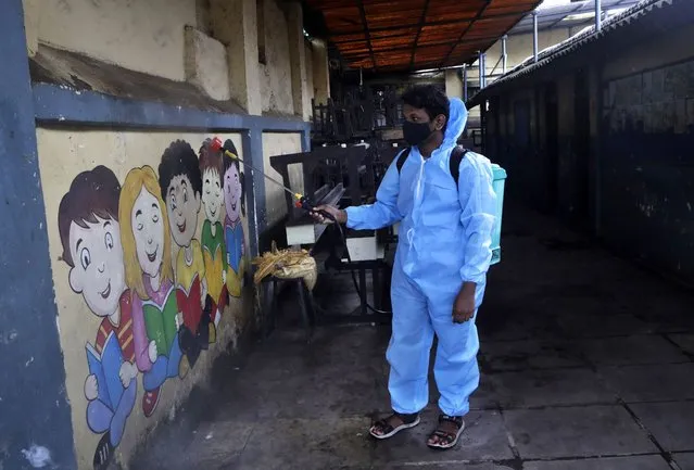 A staff member sprays disinfectant as a precautionary measure against COVID-19 ahead of reopening of the school in Dharavi, one of Asia's largest slums, in Mumbai, India, Friday, October 1, 2021. Authorities have asked teachers and students to strictly follow the guidelines as schools for higher level students are scheduled to reopen in India's financial capital from Oct 4. (Photo by Rajanish Kakade/AP Photo)
