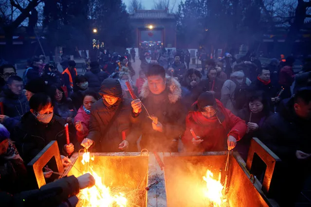 People burn incense sticks and pray for good fortune at Yonghegong Lama Temple on the first day of the Lunar New Year of the Rooster in Beijing, China January 28, 2017. (Photo by Damir Sagolj/Reuters)