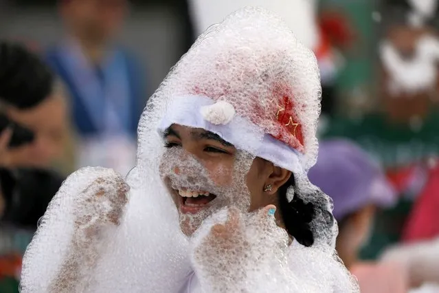 A girl wearing a Santa Claus hat plays in the foam at the end of the finish line, after the Santa Run 10-kilometre race,  in Caracas, Venezuela on December 17, 2023. (Photo by Leonardo Fernandez Viloria/Reuters)
