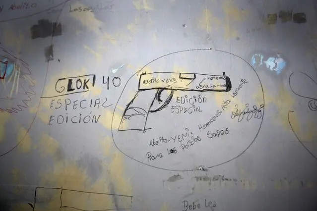 This April 7, 2015 photo shows the wall of a jail cell covered with drawings and messages inside the now empty Garcia Moreno Prison, during a guided tour for the public in Quito, Ecuador. The Spanish language messages around the drawing encourage people to kill abusive police with a Glock special edition 40 gun. Part of it reads “Brothers. Until death. For the abusive police”. (Photo by Dolores Ochoa/AP Photo)