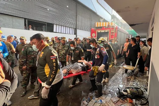 Rescue workers carry an injured person on a stretcher at the site of a fire at the Grand Diamond City hotel-casino in Poipet on December 29, 2022. As many as 10 people have died in a fire in a Cambodian hotel-casino on the border of Thailand, police said December 29. (Photo by AFP Photo/Stringer)