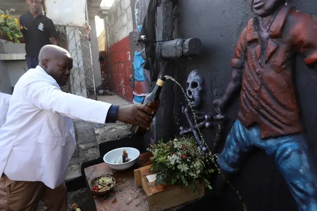 Cemetery director Raymond Valcin gives an offering of alcohol at a gravesite during Day of the Dead celebrations, in Port-au-Prince, Haiti on November 1, 2021. (Photo by Ralph Tedy Erol/Reuters)