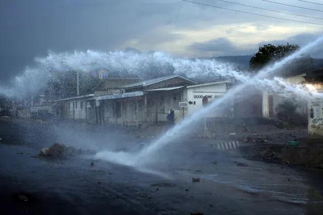 A police officer keeps an eye on demonstrators as a water canon clears barricades in the Nyakabyga district of Bujumbura, Burundi, Friday, May 8, 2015. (Photo by Jerome Delay/AP Photo)