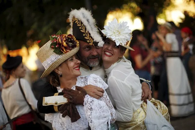 A man (C) dressed in early nineteenth century French army uniform and women dressed as bourgeoises pose for a friend as they participate in the third edition of “Ronda Romantica” (Romantic Ronda) in Ronda, southern Spain, May 16, 2015. (Photo by Jon Nazca/Reuters)