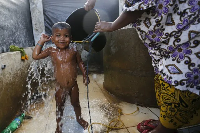 A Rohingya migrant woman, who arrived in Indonesia by boat, showers her child inside a temporary compound for refugees in Kuala Cangkoi village in Lhoksukon, Indonesia's Aceh Province May 17, 2015. (Photo by Reuters/Beawiharta)