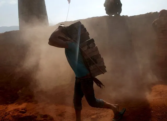 A man carries bricks on his back as dust billows at a brick factory in Bhaktapur, Nepal, May 17, 2015. (Photo by Ahmad Masood/Reuters)