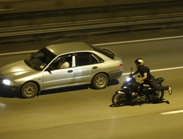 A motorcyclist performs a stunt on a highway in Kuala Lumpur, Malaysia, September 14, 2014. (Photo by Olivia Harris/Reuters)